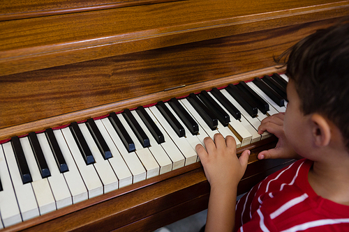 Close up of boy playing piano in classroom at school