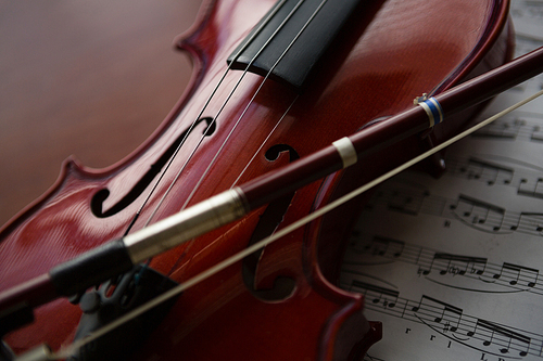 Close up of brown violin with sheet music on table at classroom