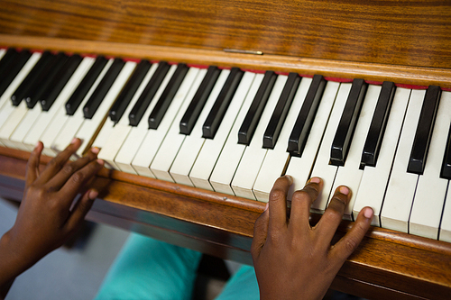 High angle view of boy playing piano while sitting in classroom at school