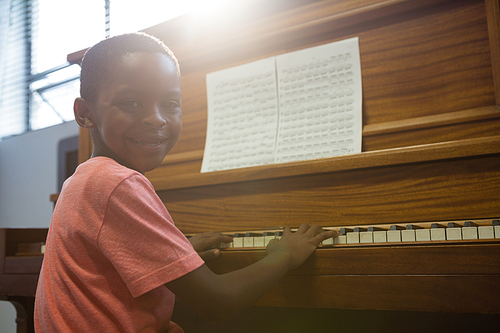 Portrait of boy playing piano in classroom at school