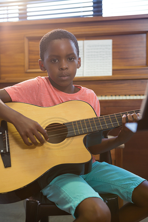 Portrait of boy playing guitar in class at music school