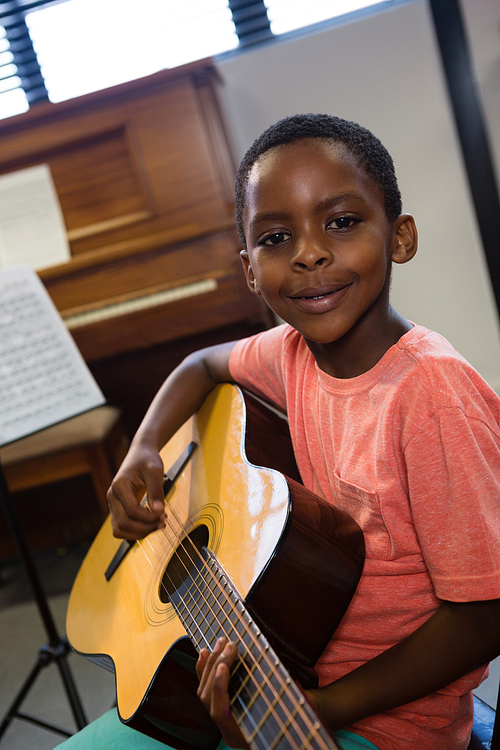 Portrait of boy holding guitar in class at music school