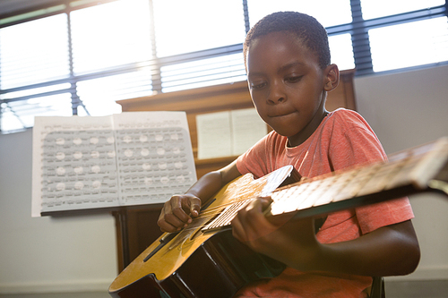 Boy playing guitar in class at music school