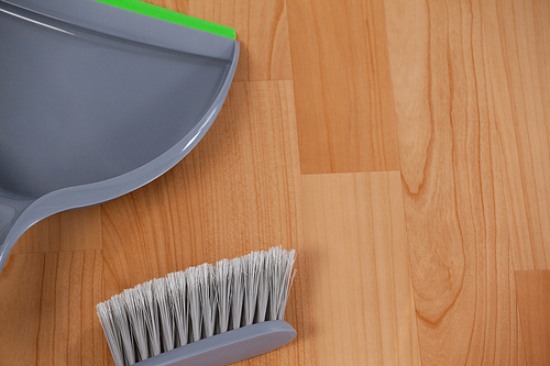 Close-up of dustpan and sweeping brush on wooden floor