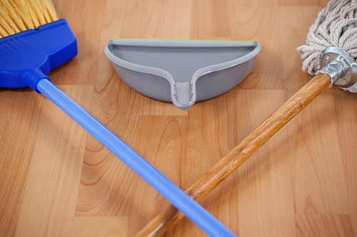 Close-up of dustpan, sweeping broom and mop on wooden floor