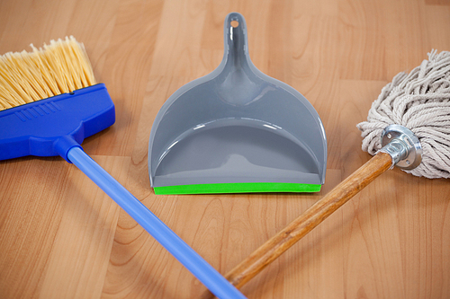 Close-up of dustpan, sweeping broom and mop on wooden floor