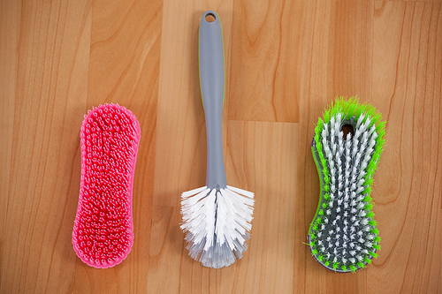 Close-up of three cleaning brushes on wooden floor