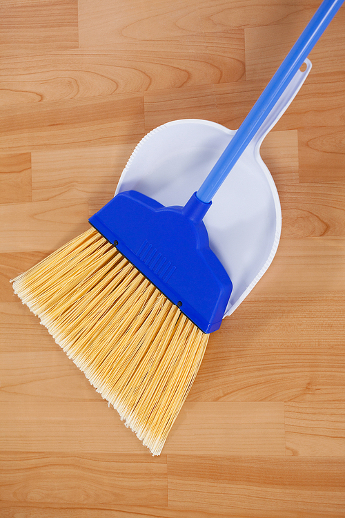 Close-up of sweeping broom with dustpan on wooden floor