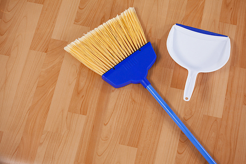 Close-up of sweeping broom and dustpan on wooden floor