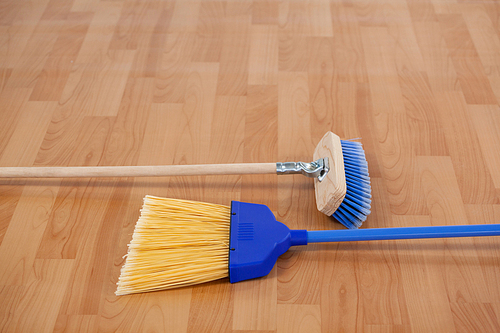 Close-up of two sweeping brooms on wooden floor