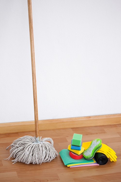Mop and cleaning equipment on wooden floor against wall