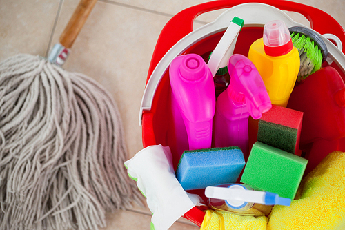 Close-up of bucket with cleaning supplies and mop on tile floor