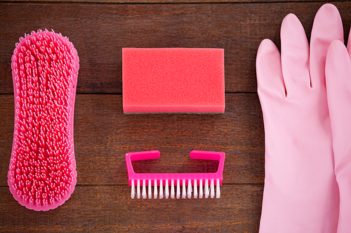 Close-up of pink color cleaning equipment arranged on wooden floor