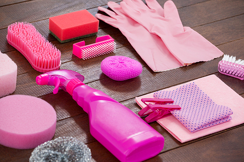 Close-up of pink color cleaning equipment arranged on wooden floor