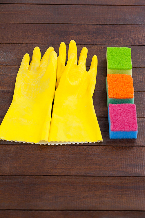 Close-up of glove and scrubber arranged on wooden floor