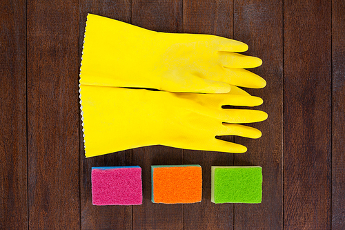 Close-up of glove and scrubber arranged on wooden floor