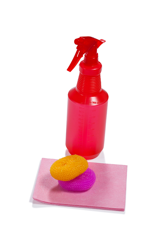 Cleaning spray bottle and dish scrubber on white background