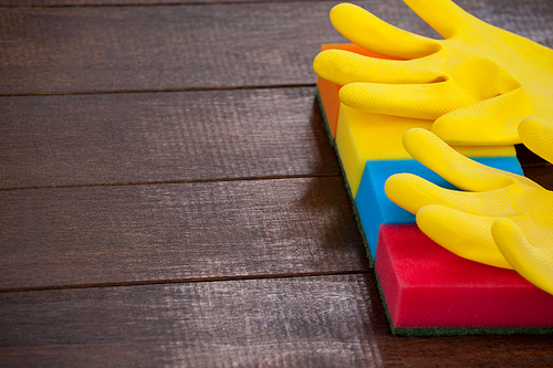 Close-up of yellow gloves with scouring pad on a wooden floor