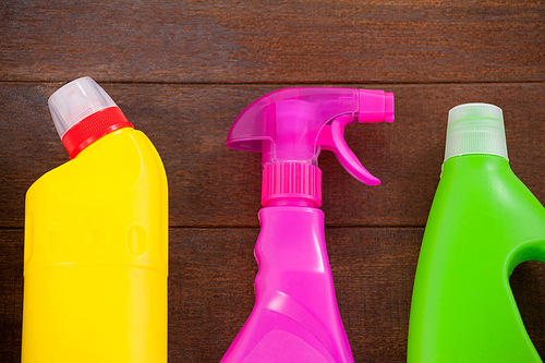 Close-up of detergent bottles and spray bottle arranged on a wooden floor