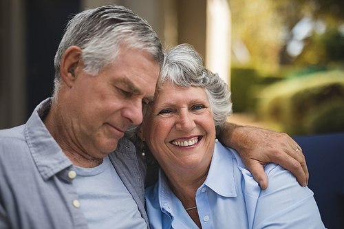 Portrait of smiling senior woman embracing man at backyard