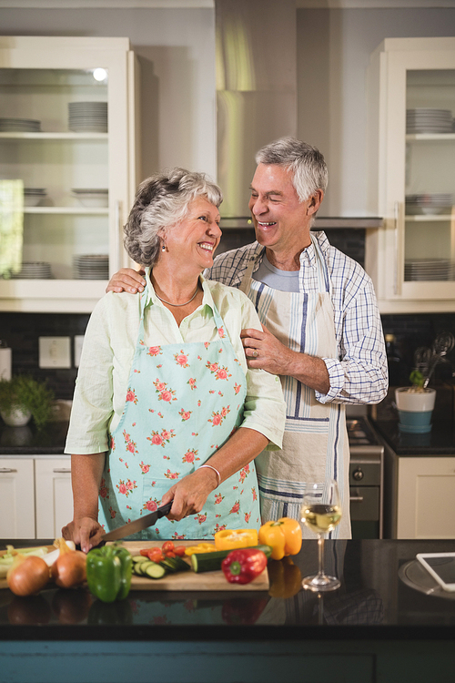 Happy senior couple standing together in kitchen at home