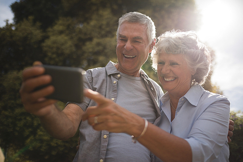 Happy senior couple looking at mobile phone on sunny day