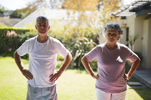 Senior couple with hands on hip exercising together on sunny day