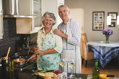 Portrait of happy senior couple preparing food together in kitchen at home