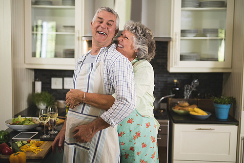 Happy senior couple embracing in kitchen at home