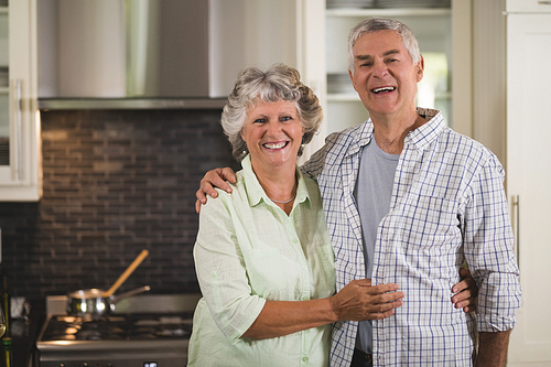 Portrait of happy senior couple standing in kitchen at home