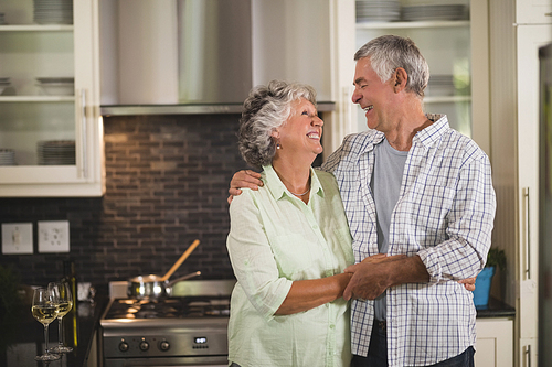 Cheerful senior couple embracing in kitchen at home