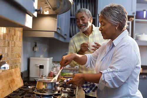 Happy senior couple preparing food while standing in kitchen at home