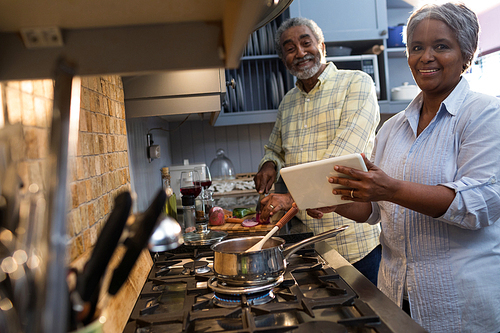 Portrait of smiling couple preparing food in kitchen at home