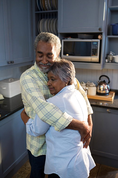 Affectionate couple embracing while standing in kitchen at home