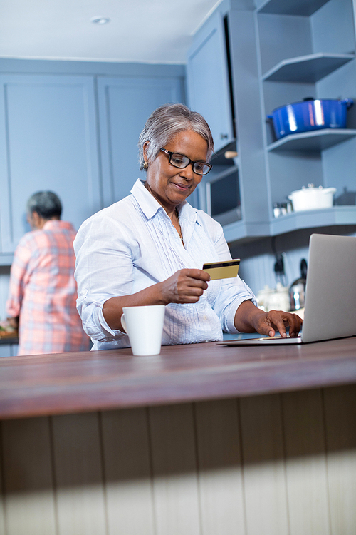 Smiling woman using credit card while doing online shopping at home