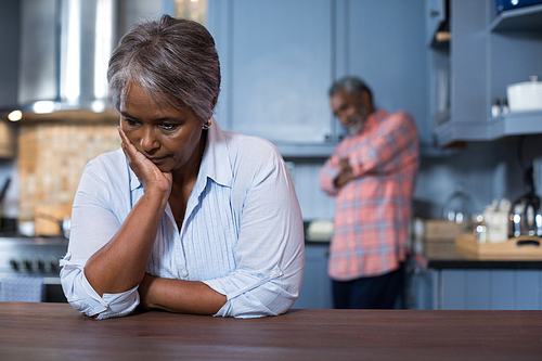 Sad woman with man in background at home