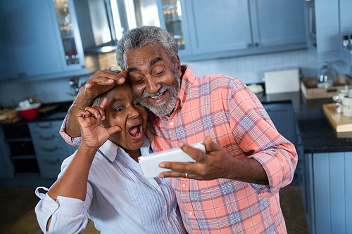 High angle view of senior couple taking selfie while standing in kitchen at home
