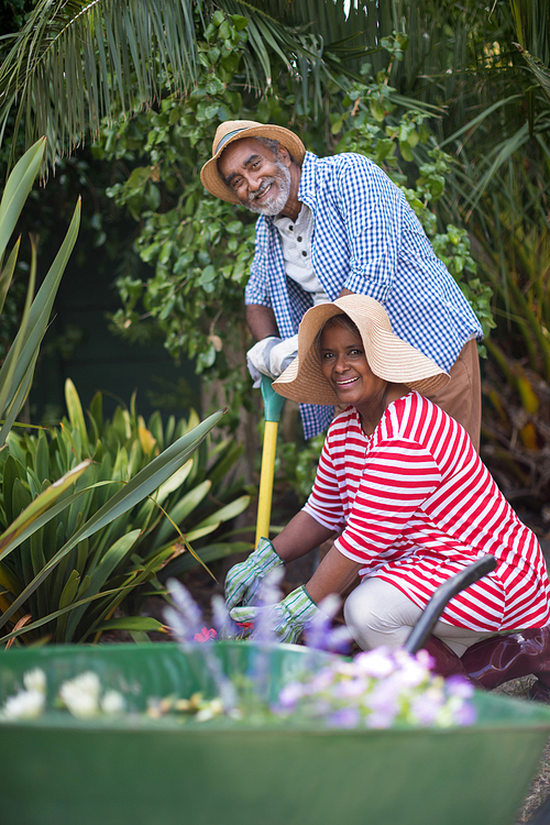 Portrait of happy senior couple gardening in yard