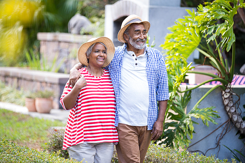 Smiling senior couple with arm around walking in yard