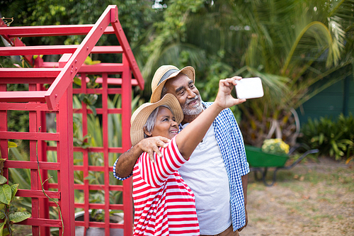 Smiling senior couple taking selfie while standing in yard