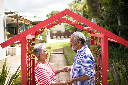 High angle view of couple holding hand while standing by metallic structure in yard