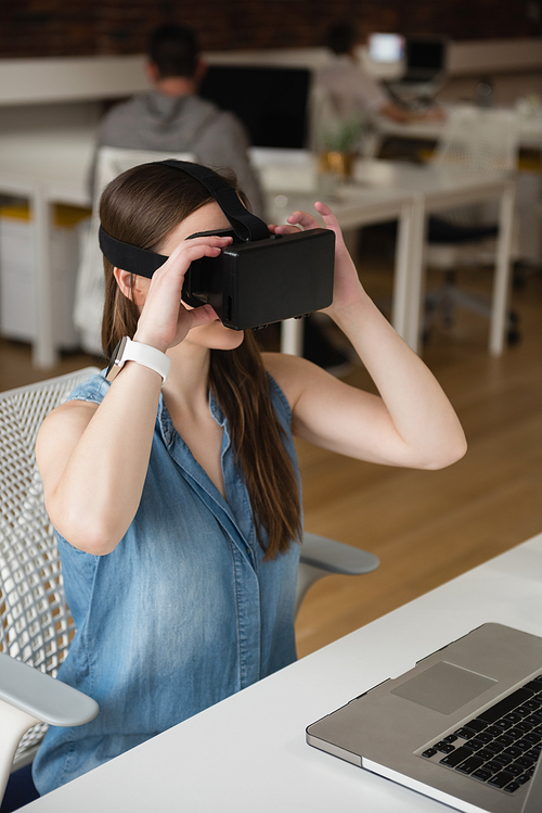Female executive using virtual reality headset in office