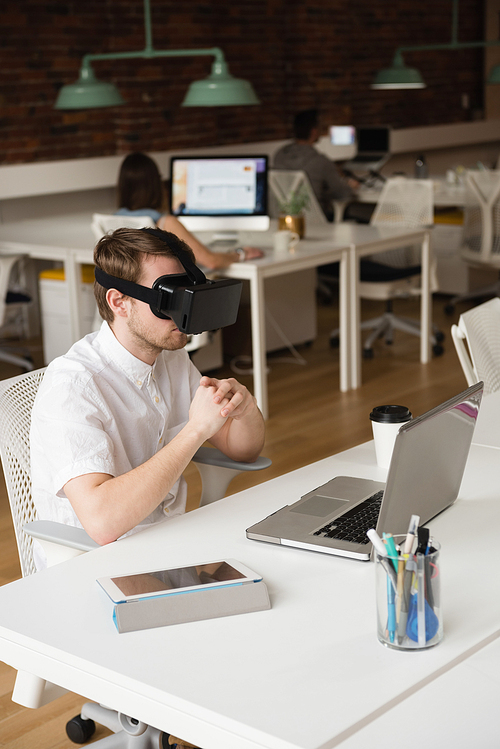 Male executive using virtual reality headset in office