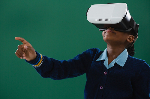 Schoolgirl using virtual reality headset against chalkboard