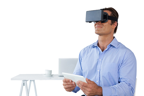 Businessman holding tablet while wearing vr glasses against white background