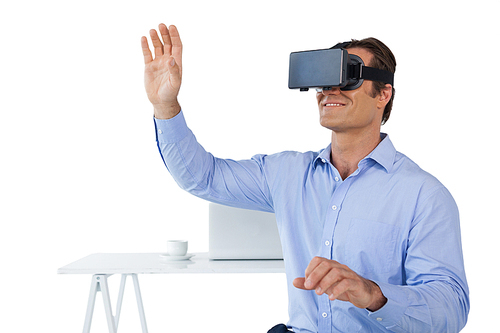 Smiling businessman with arms raised using vr glasses while sitting against white background