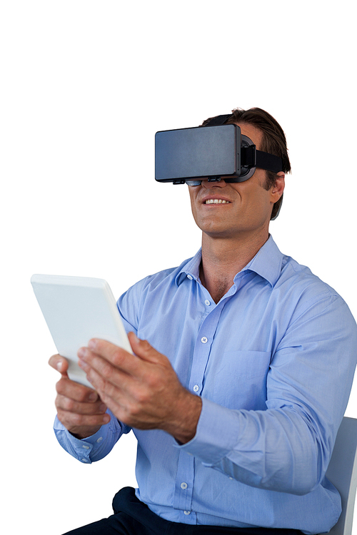 Businessman with tablet sitting on chair while using vr glasses against white background