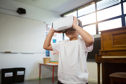 Close of boy holding virtual reality simulator while standing against piano at home