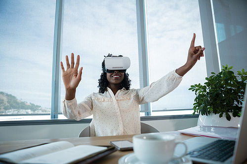 Female executive using virtual reality headset at desk in office