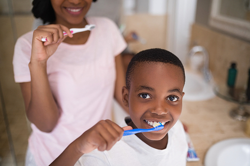 Portrait of boy with mother brushing teeth at home